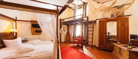 Un dormitorio tradicional con cama con dosel, alfombra roja y armario de madera.