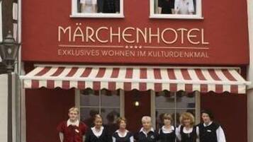 A hotel named Märchenhotel with a red facade and a striped awning.