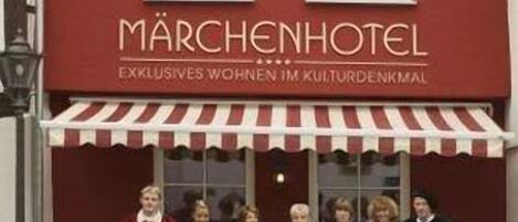 A hotel named Märchenhotel with a red facade and a striped awning.