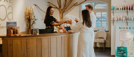 A reception area with a wooden counter, a large tree branch decoration, and a Nuxe product display.