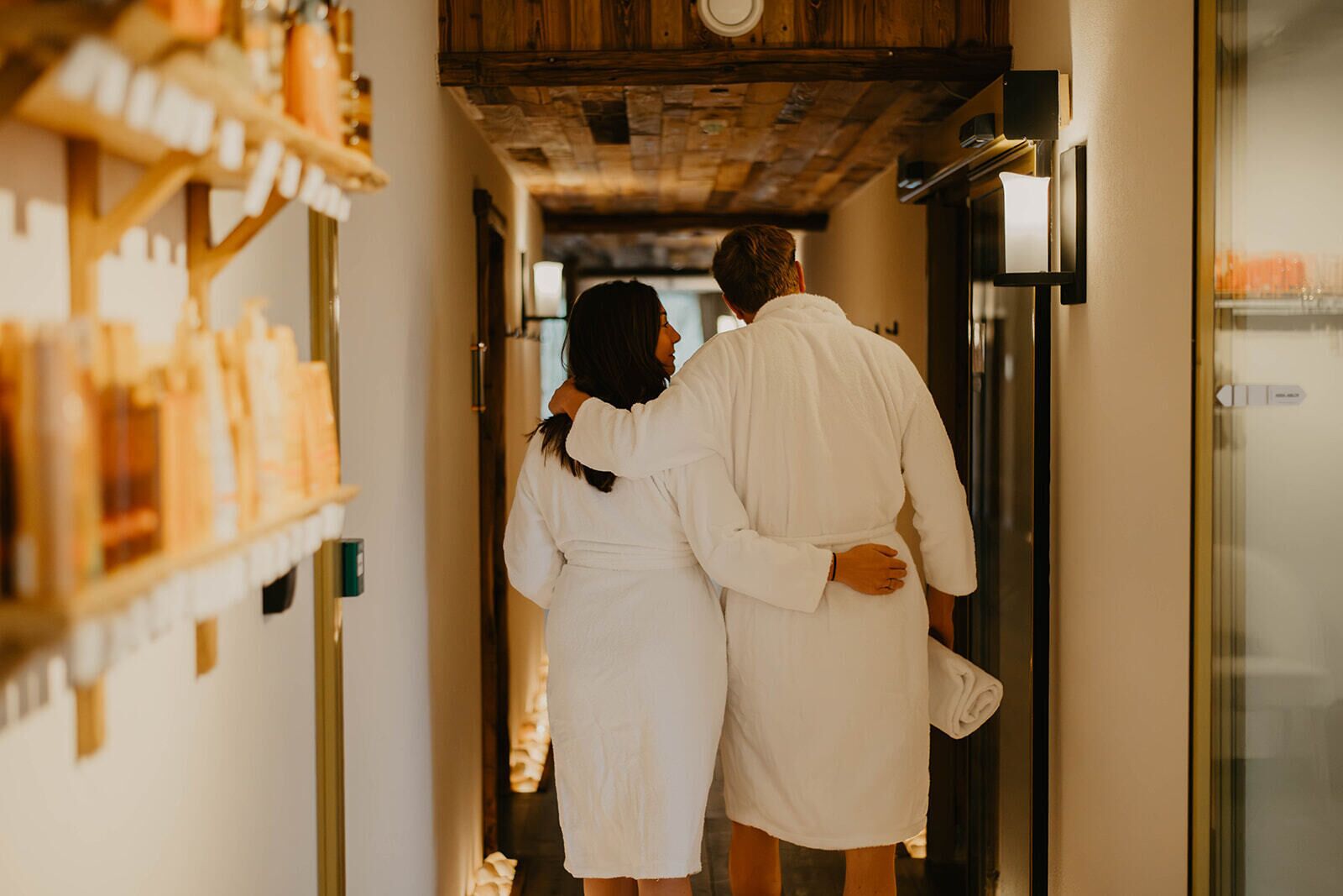 Una pareja en un pasillo con techo de madera y una puerta de vidrio a la derecha.