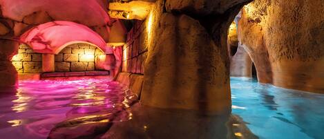 An indoor pool with stone walls and a pink ceiling.