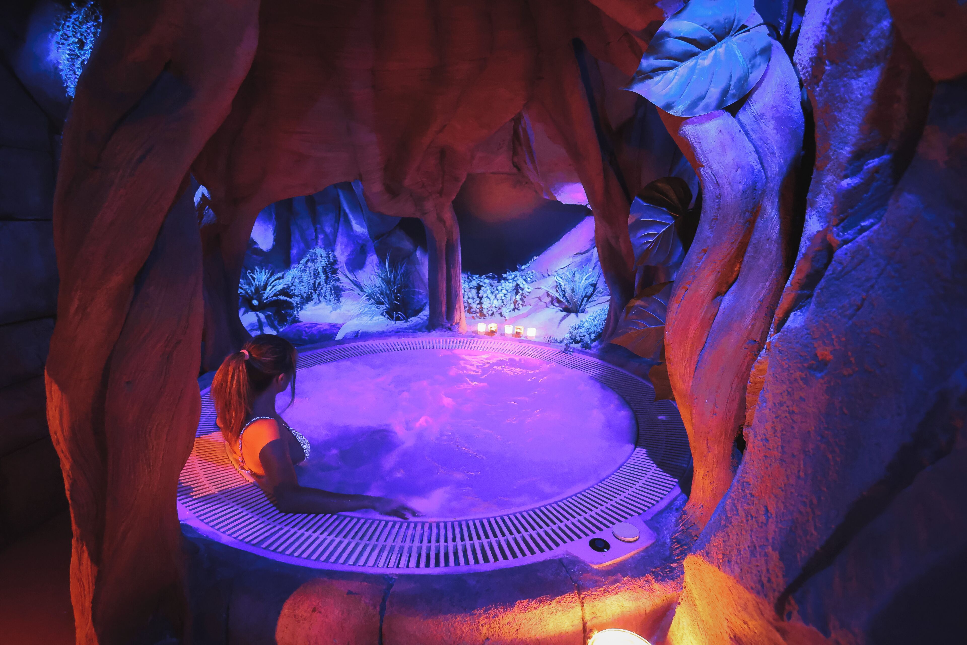 A hot tub in a cave-like setting with a person sitting inside.