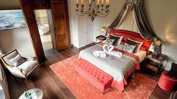 Ein geräumiges Schlafzimmer mit einem großen Bett, einer Chandelieber und Blick ins Bad.