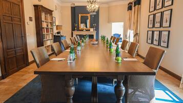 Een formele eetzaal met een lange tafel, stoelen en een kroonluchter.