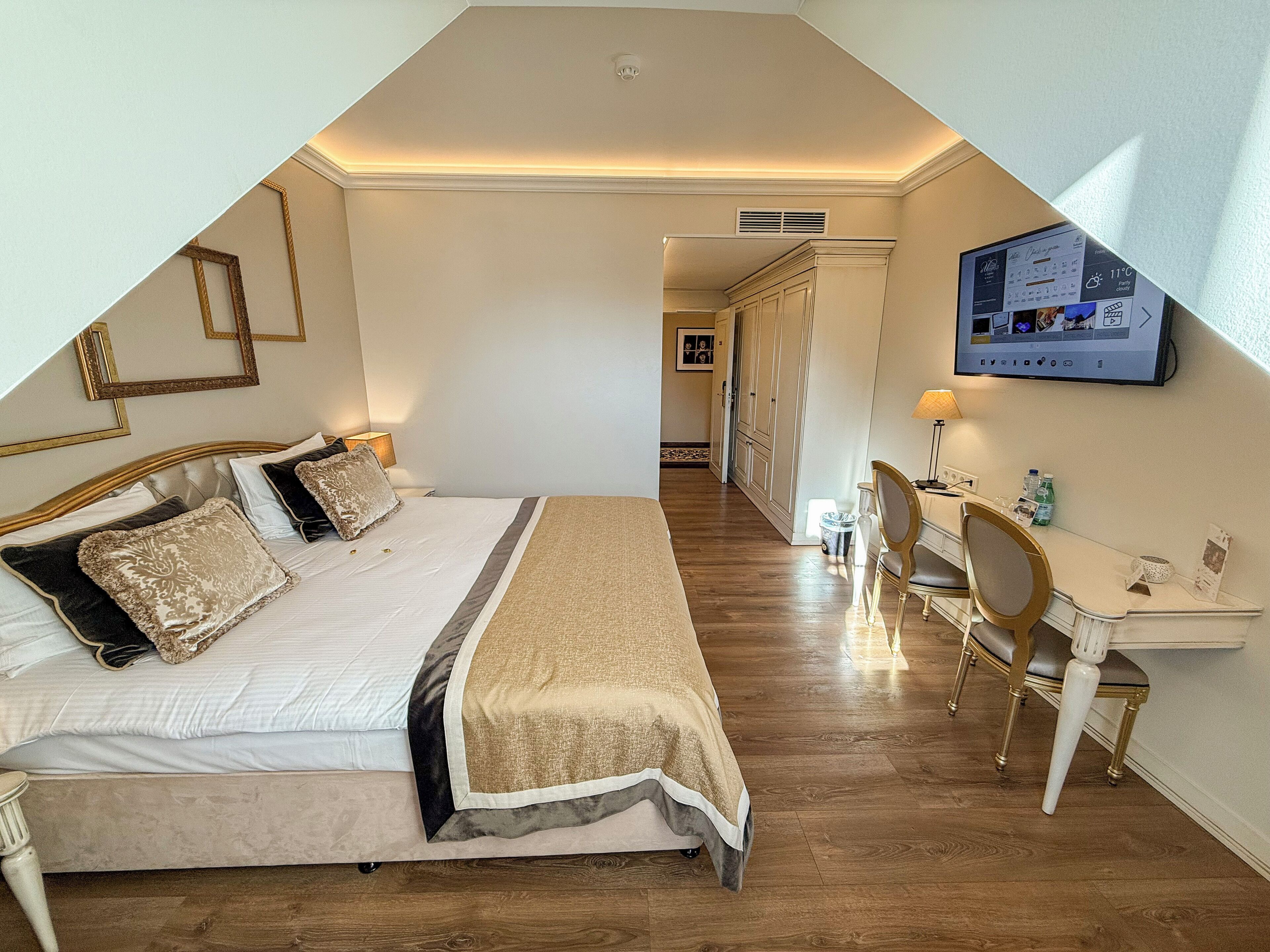 Une chambre à coucher comprenant un lit, une table de chevet, un bureau, une chaise et un téléviseur fixé au mur.