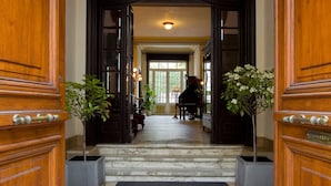 Una entrada imponente con una escalinata de mármol que conduce a un salón de piano.