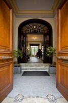 Una entrada imponente con una escalinata de mármol que conduce a un salón de piano.