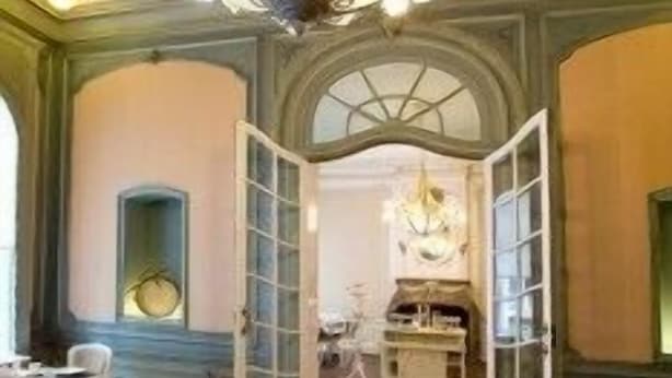 Un comedor con candelabro, mesas y sillas de madera.