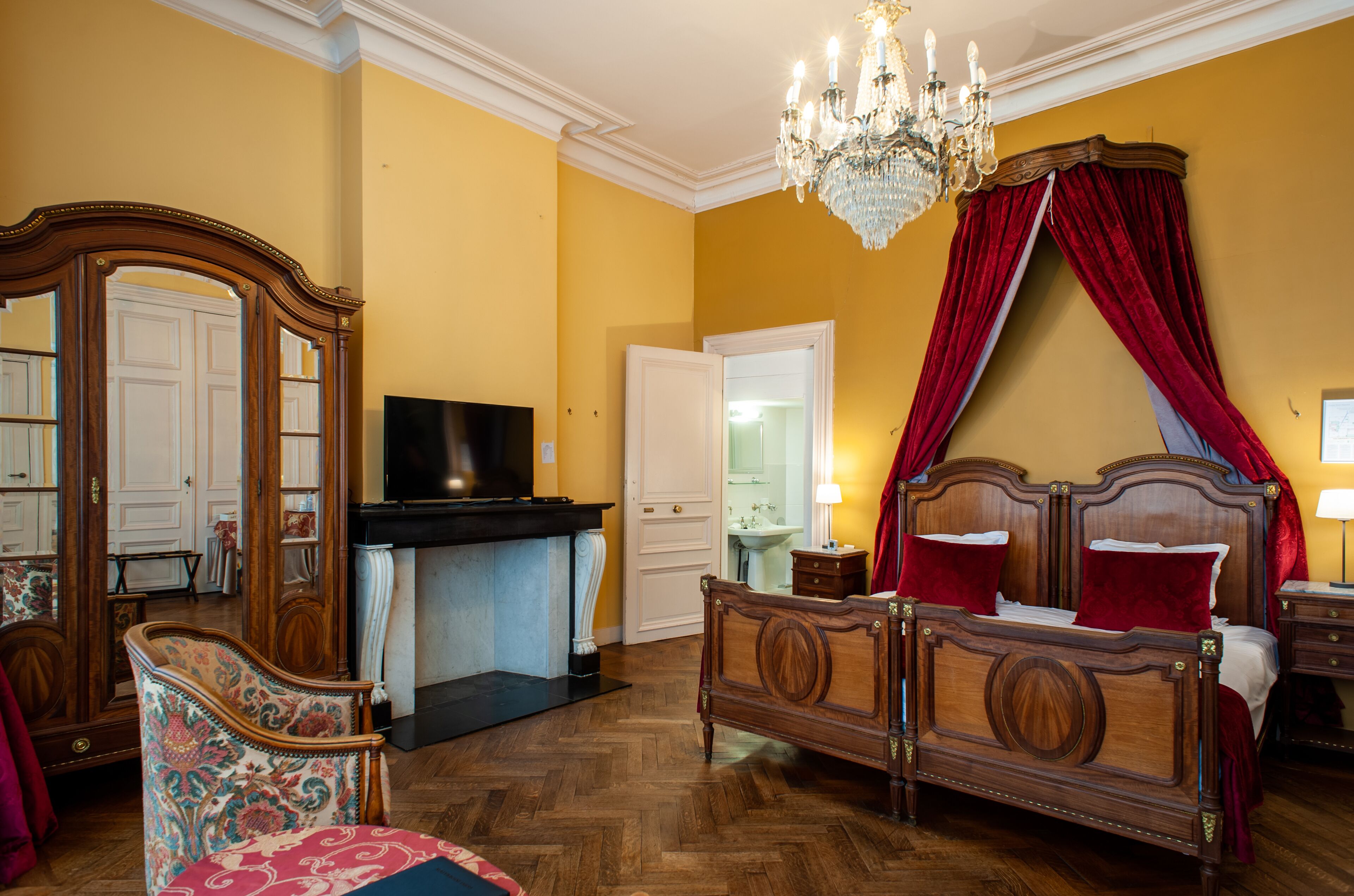 Un dormitorio con una cama de madera, televisor, candelabro y espejo.
