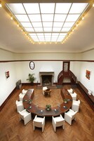 Une salle de conférence dotée d’une grande table ovale, de chaises blanches, d’une cheminée, d’un escalier en bois et d’une verrière.