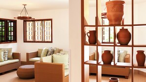 Una habitación con muebles de mimbre, una lámpara colgante y vistas a través de una ventana con diseño de cuadrícula.