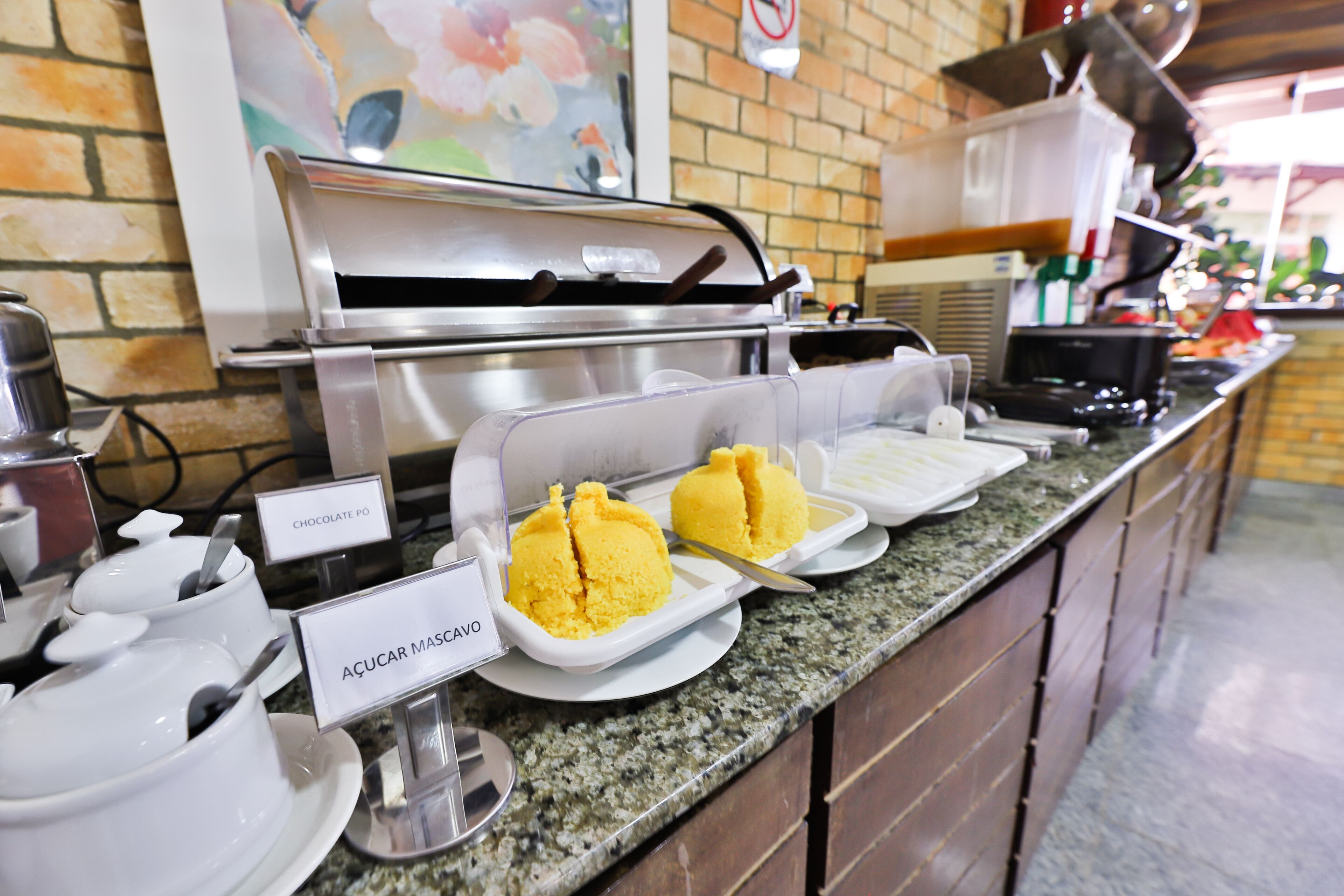 A buffet area with labeled dishes of chocolate pudding and açúcar moscado.