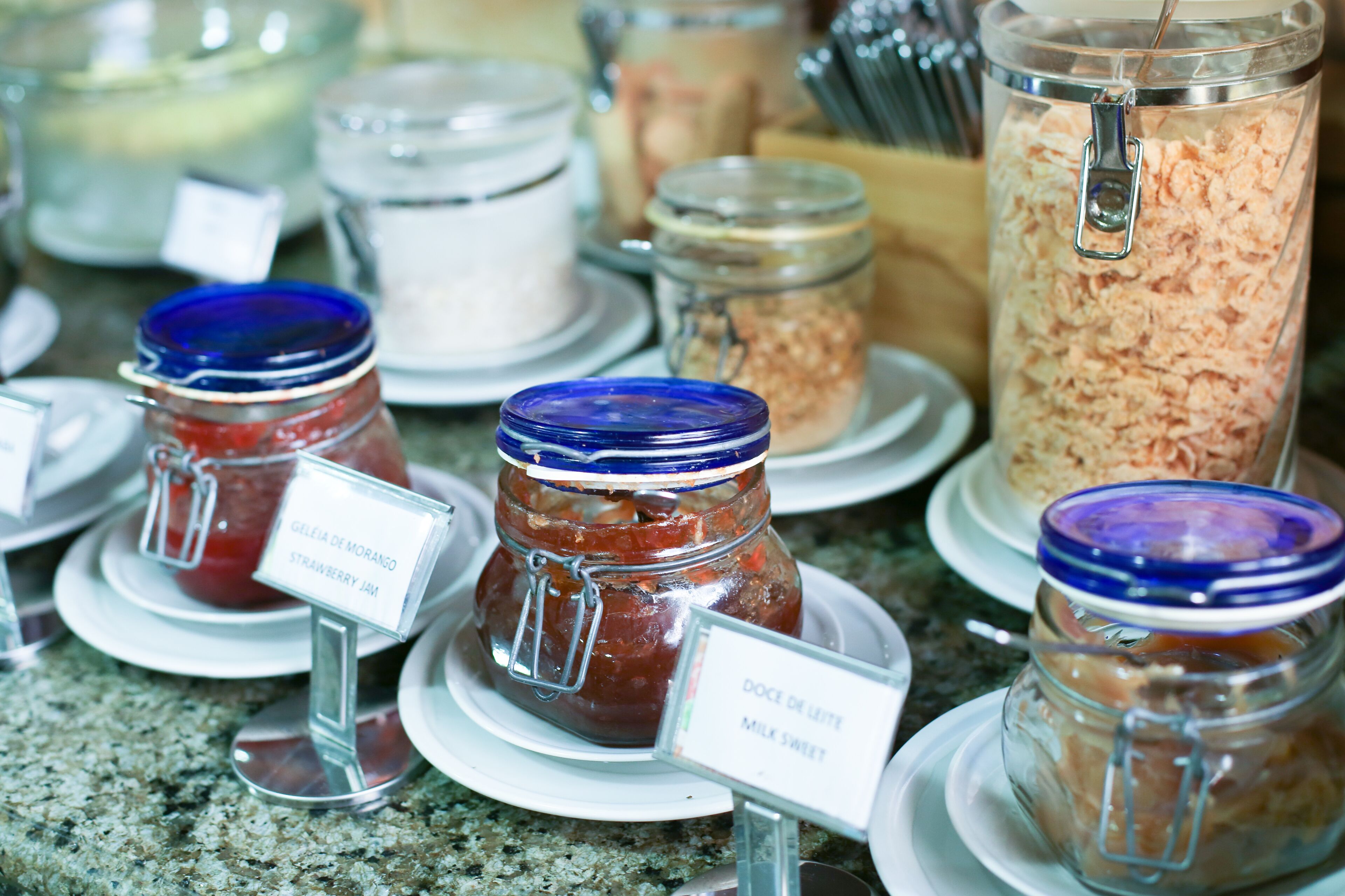 A variety of food items in jars with labels, displayed on plates.