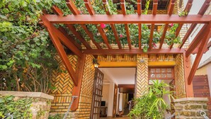 Una entrada tradicional con pérgola de madera, muros de ladrillo y patrón en espiga.