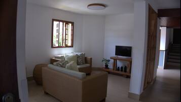 Una sala de estar con un sofá, un televisor y una ventana con persianas.