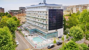 Un hotel moderno con piscina sul tetto, diversi piani e facciata in vetro.