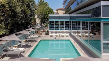 Una piscina al aire libre de temporada, sombrillas