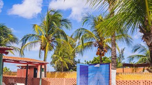 Piscina com espreguiçadeiras, palmeiras e uma estrutura em azulejo azul.