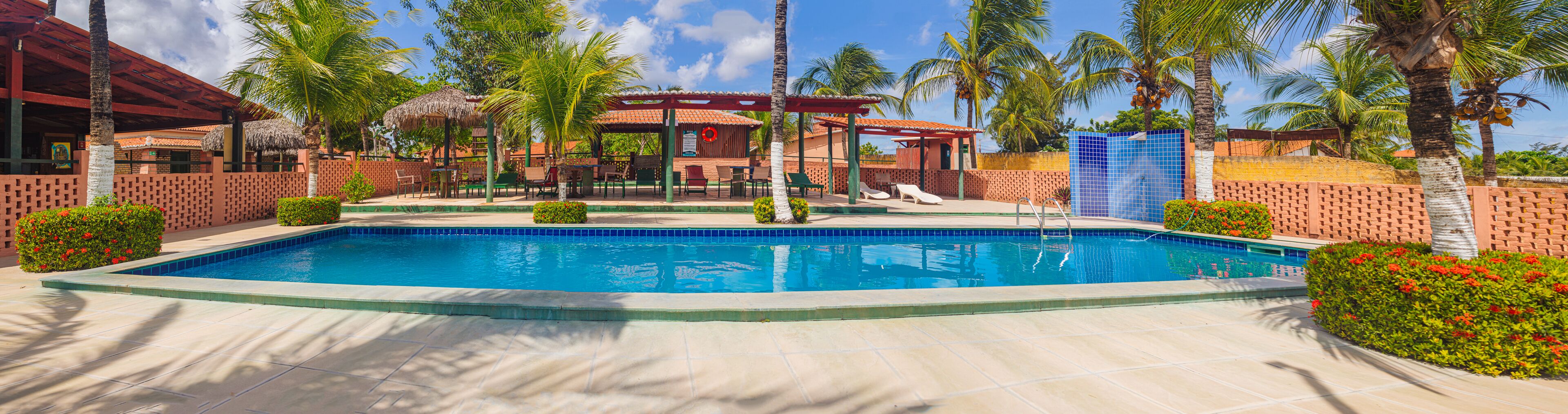 A swimming pool surrounded by palm trees and a covered seating area.