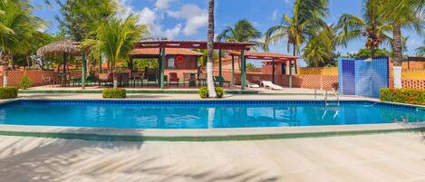 A swimming pool surrounded by palm trees and a covered seating area.
