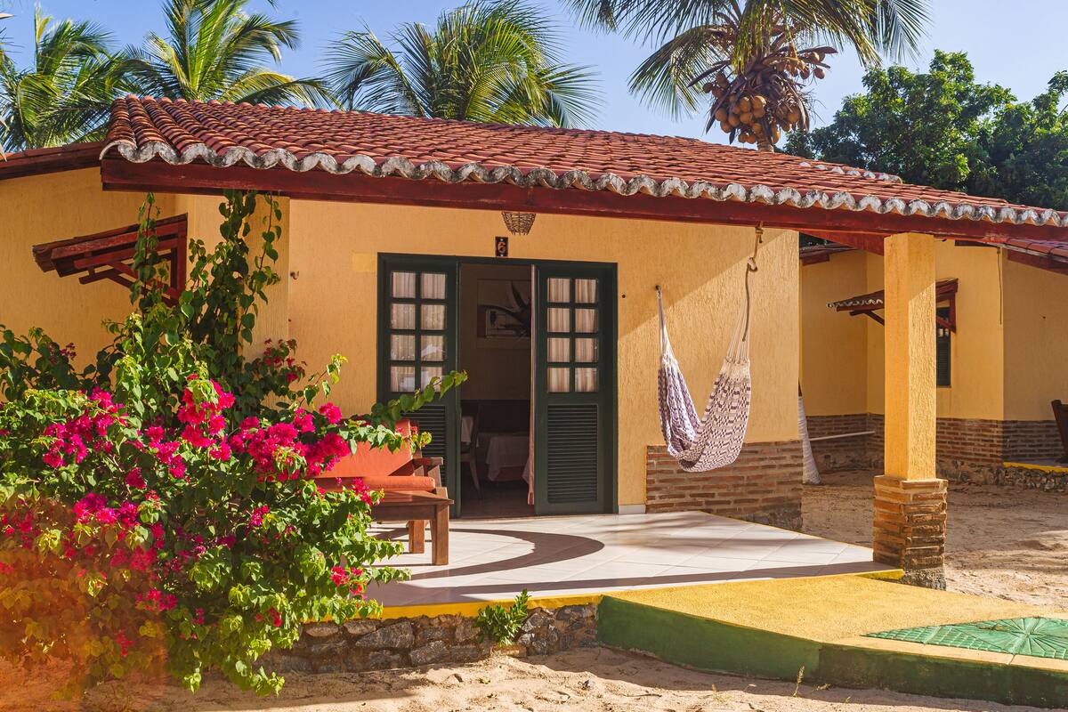 A building with a tiled roof, a door with shutters, and a hammock hanging from the ceiling.