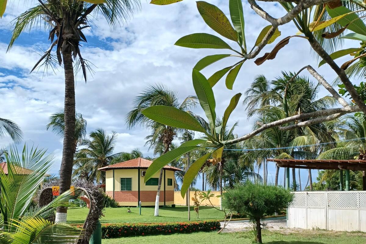 A well-maintained garden with palm trees, a lawn, and a building with a red roof.