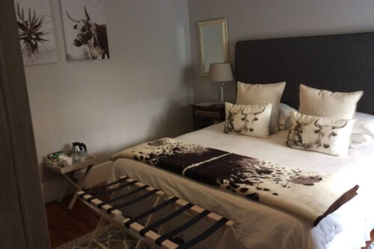 A bedroom with a bed, pillows, a bedside table, and wall art.
