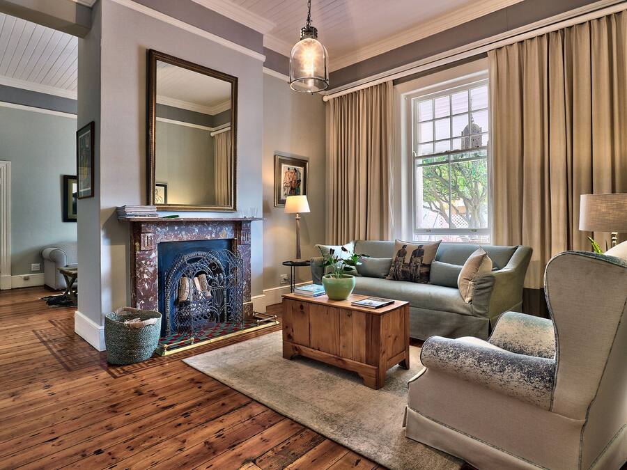 A living room with a fireplace, a sofa, a chair, and a large window with curtains.