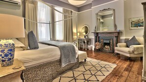 A bedroom with a bed, bedside table, lamp, and a large mirror. - Parker Cottage (Cape Town)