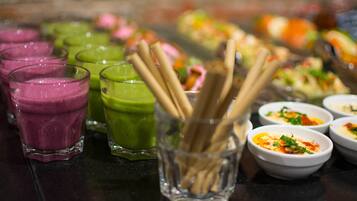 Variedad de bebidas coloridas y pequeños recipientes con comida sobre una mesa.