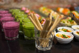 Variedad de bebidas coloridas y pequeños recipientes con comida sobre una mesa.