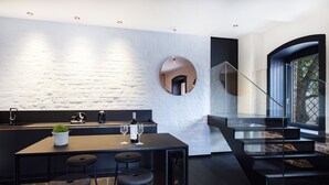 Una cocina moderna con una isla central, taburetes de bar y una copa de vino.