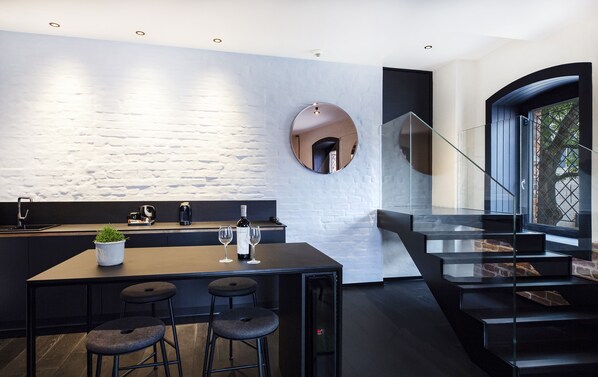 Een moderne keuken met een centraal eiland, een paar barkrukken en een wijnglas.