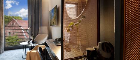 Une chambre d’hôtel moderne dotée d’une grande fenêtre, d’un fauteuil confortable, d’une petite table et d’un coin café.
