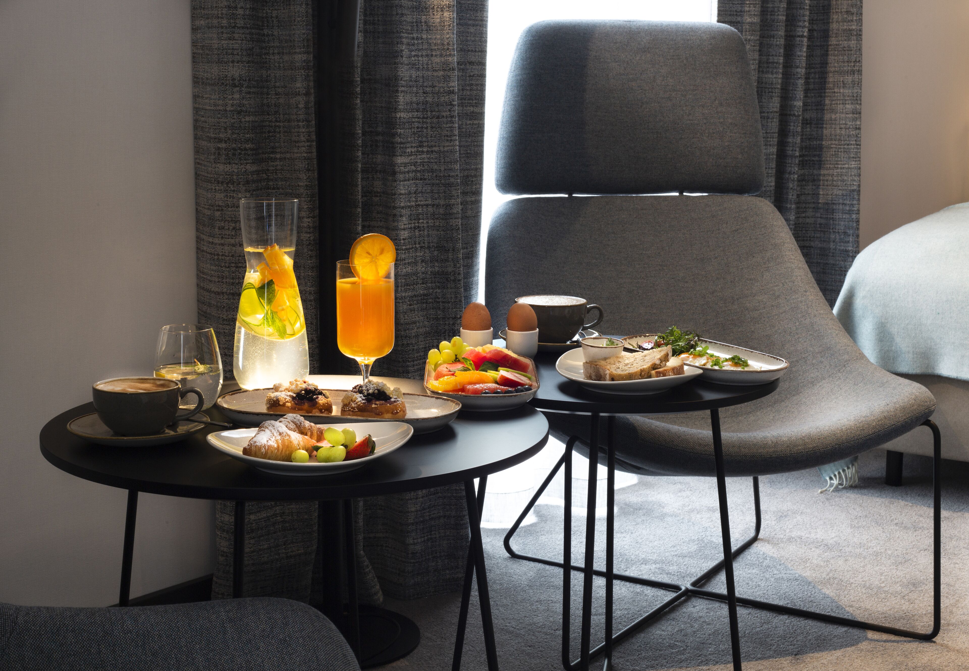 Une table à manger avec des aliments pour le petit-déjeuner, notamment des croissants, des fruits et un verre de jus d’orange.