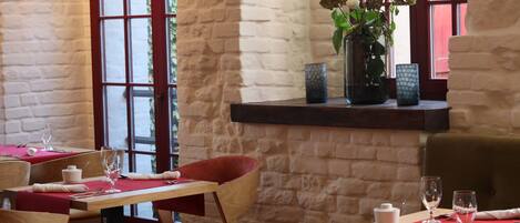Un interior de restaurante con paredes de piedra, mesas de madera y sillas rojas.