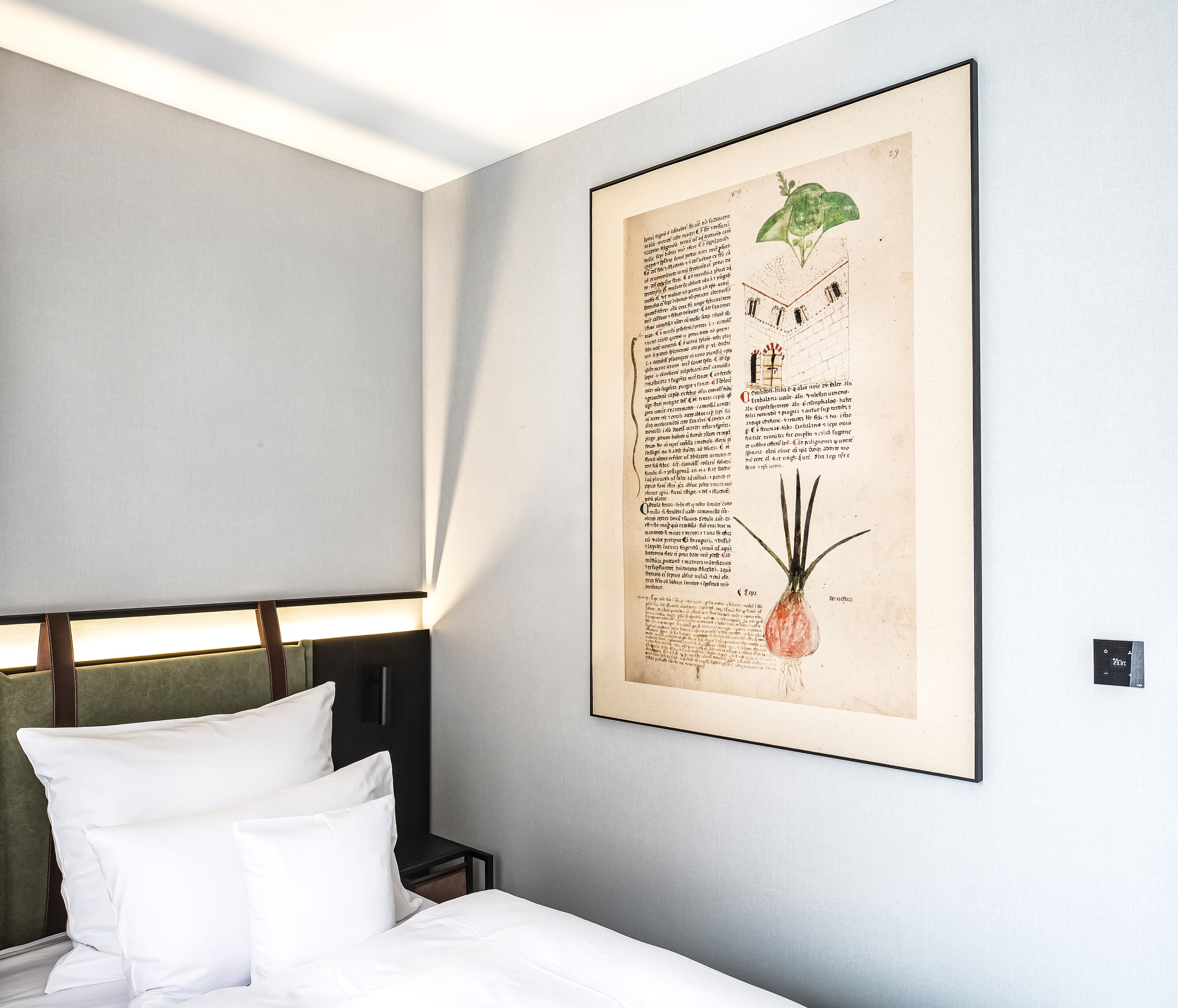 A neatly made bed with white linens and pillows, a framed botanical illustration on the wall, and a modern headboard.