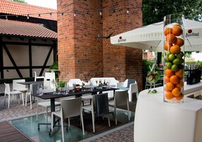 An outdoor dining area with a brick wall, white tables, and chairs.