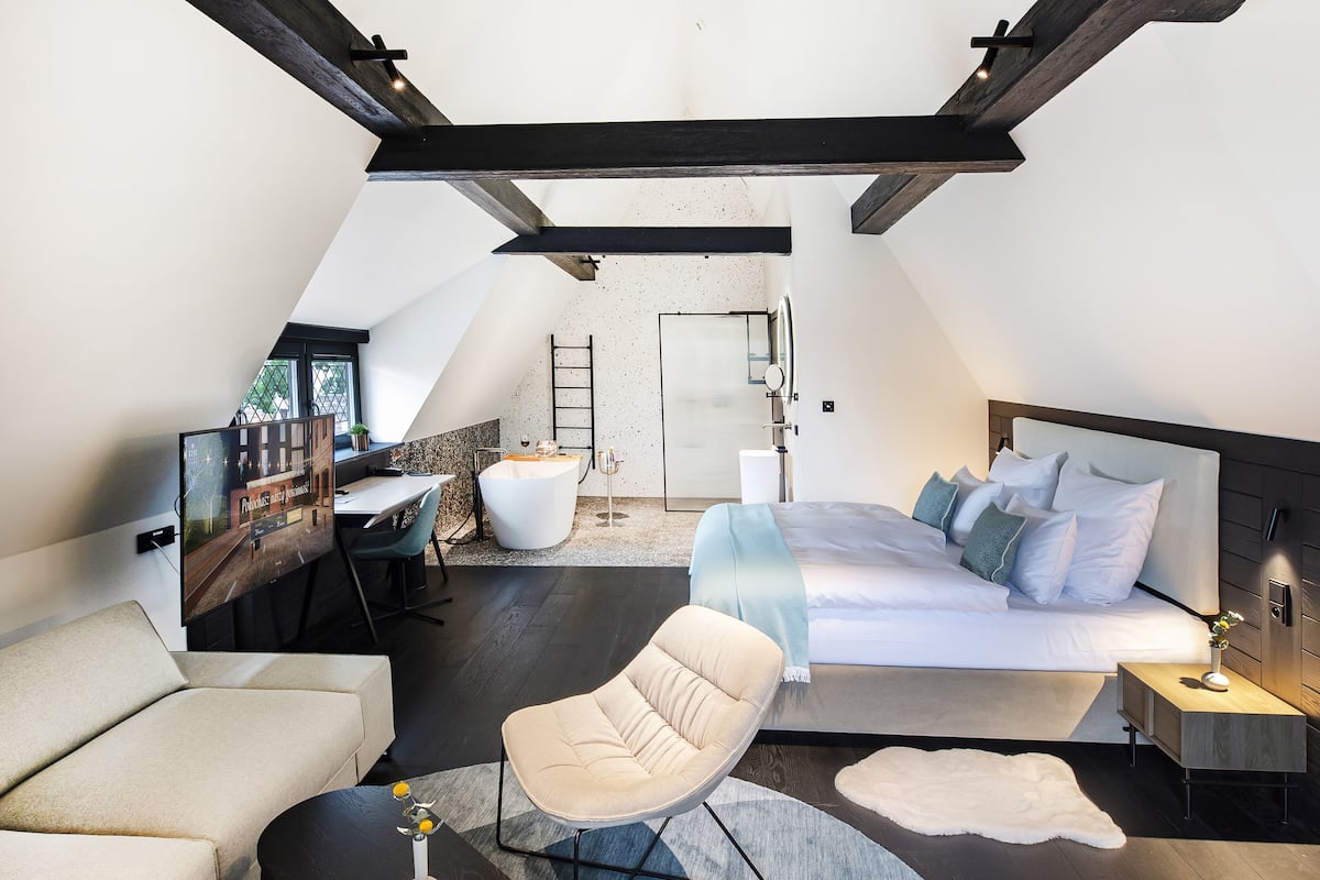 A modern bedroom with a large bed, a desk, and a chair.