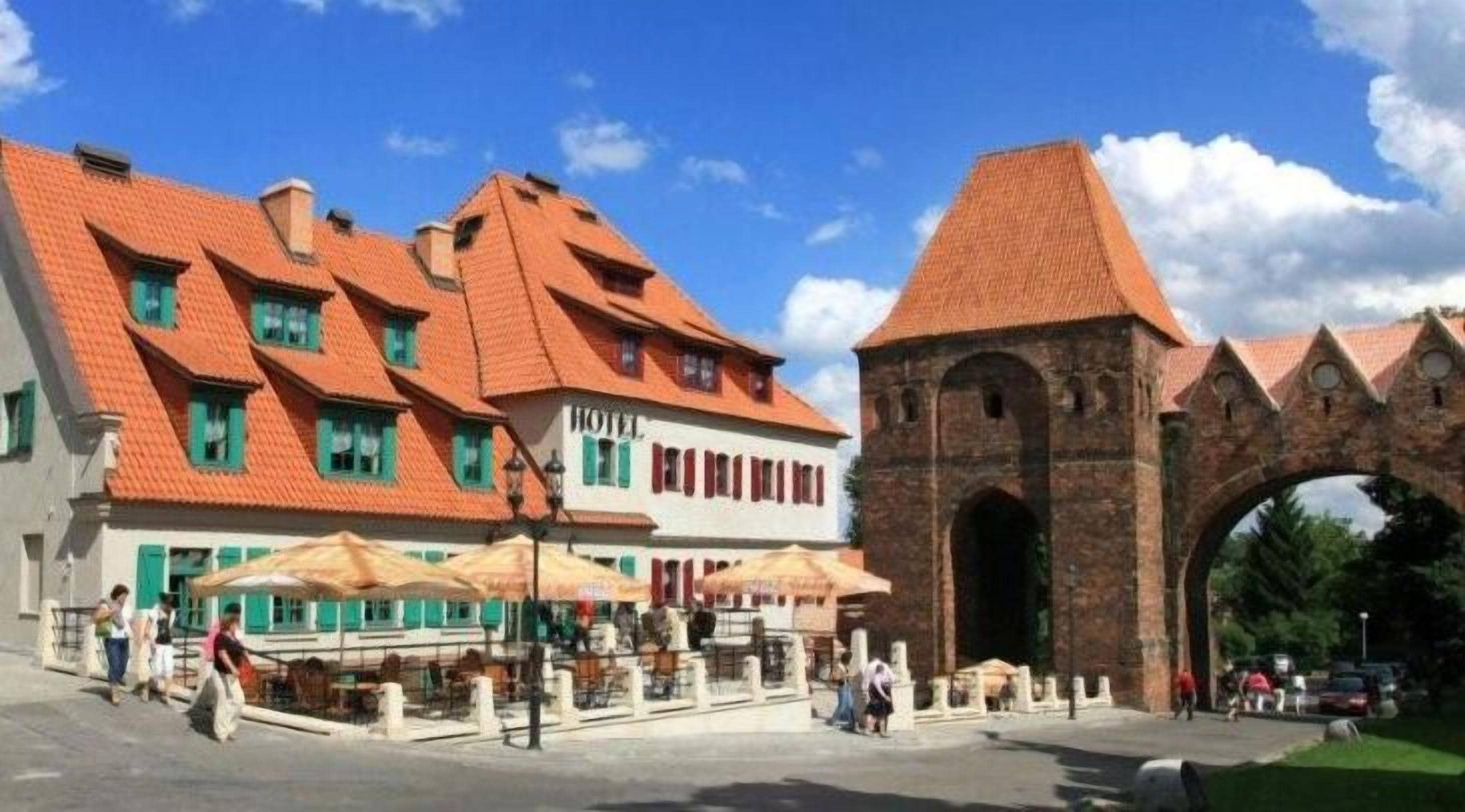 Ein traditionelles Gebäude mit rotem Ziegeldach, einem steinernen Bogen und einem Schild, das es als Hotel kennzeichnet.