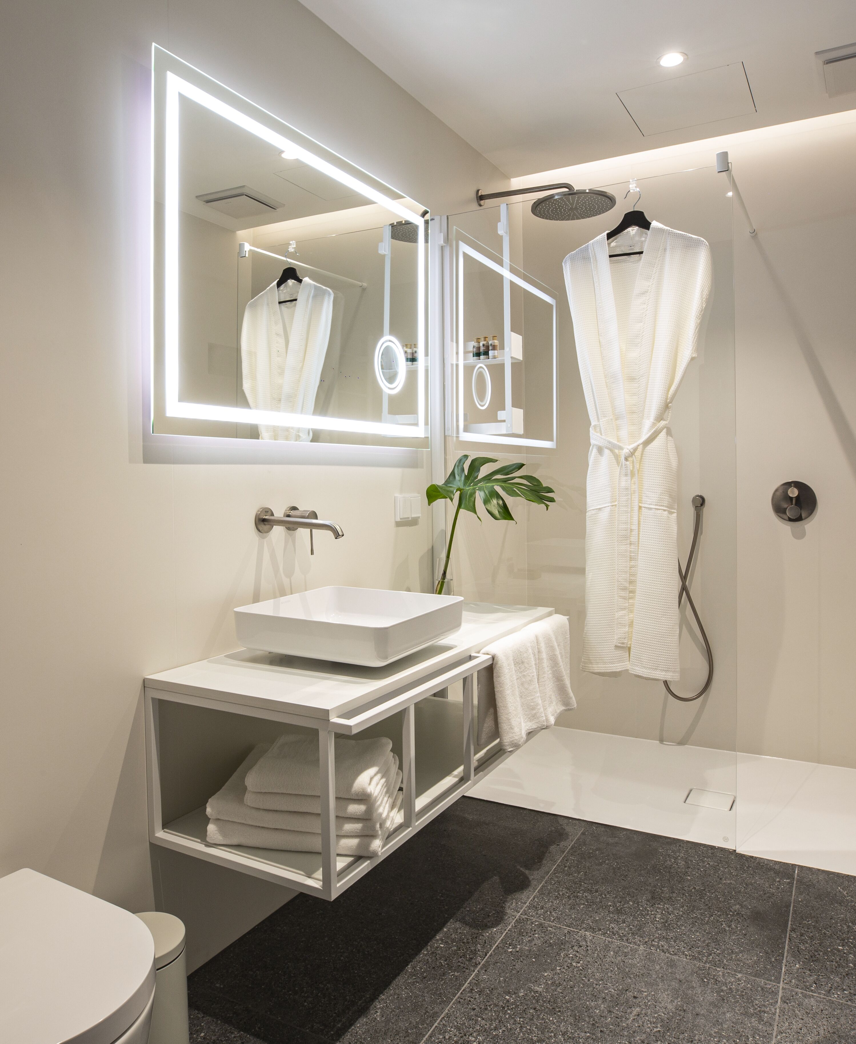 Een moderne badkamer met een grote spiegel, een wit wastafelmeubel en een douche.