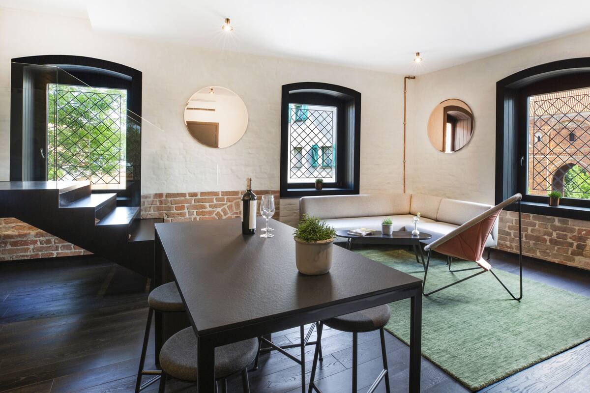 A modern interior with a dining area, a sofa, and a window with a view of a brick building.