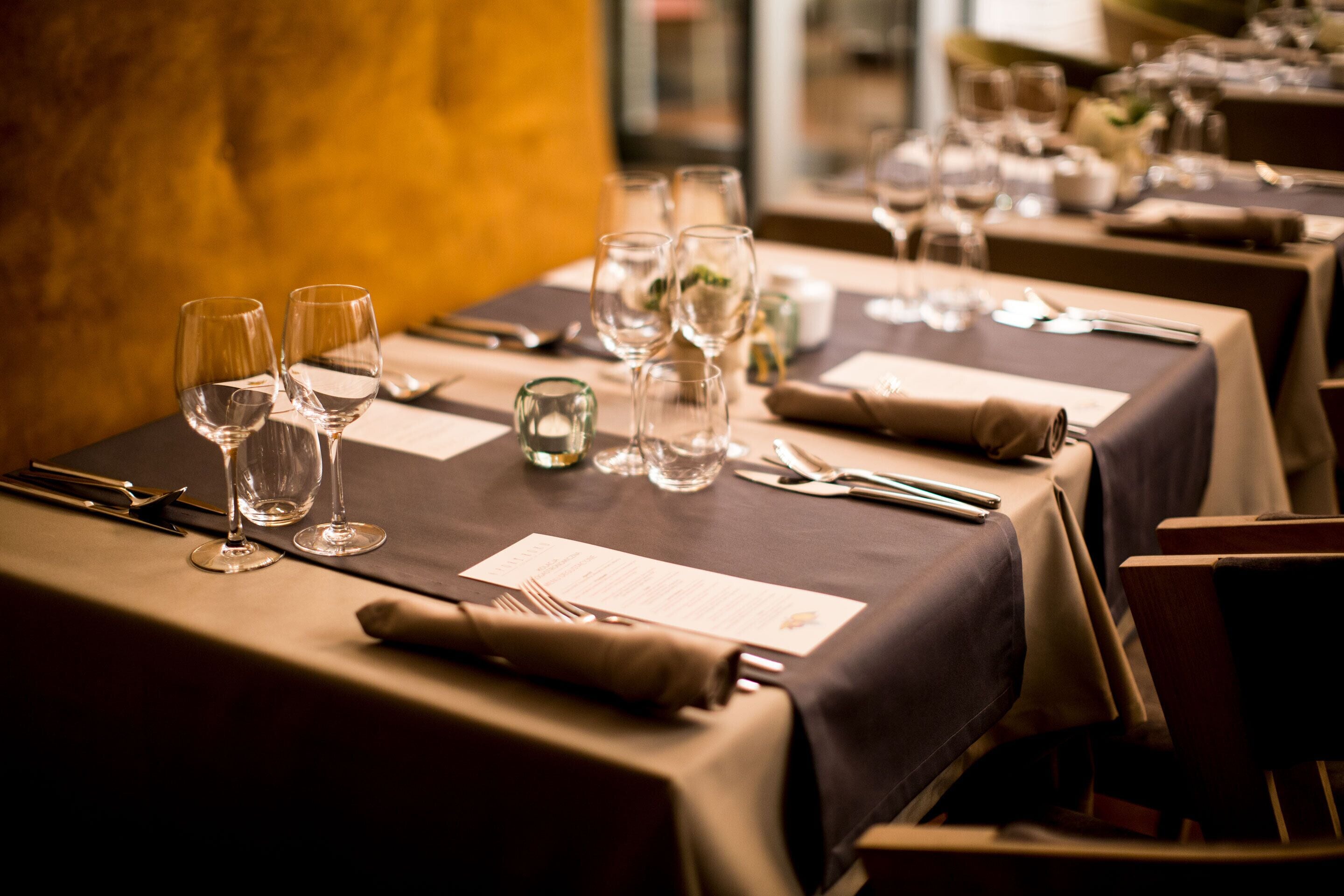 A dining table set with wine glasses, cutlery, and a menu.