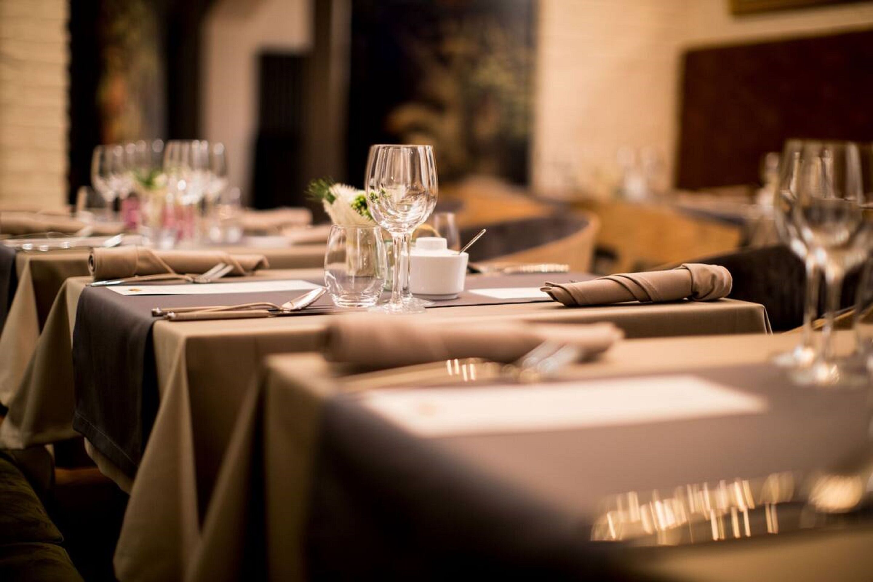 A restaurant setting with tables set for dining, featuring neatly arranged cutlery and glassware.