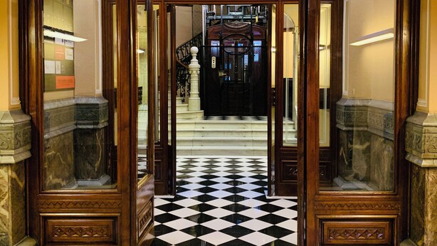 A grand entrance with a black and white checkered floor, leading to a staircase and an elevator. - Hip Karma Hostel (Barcelona)