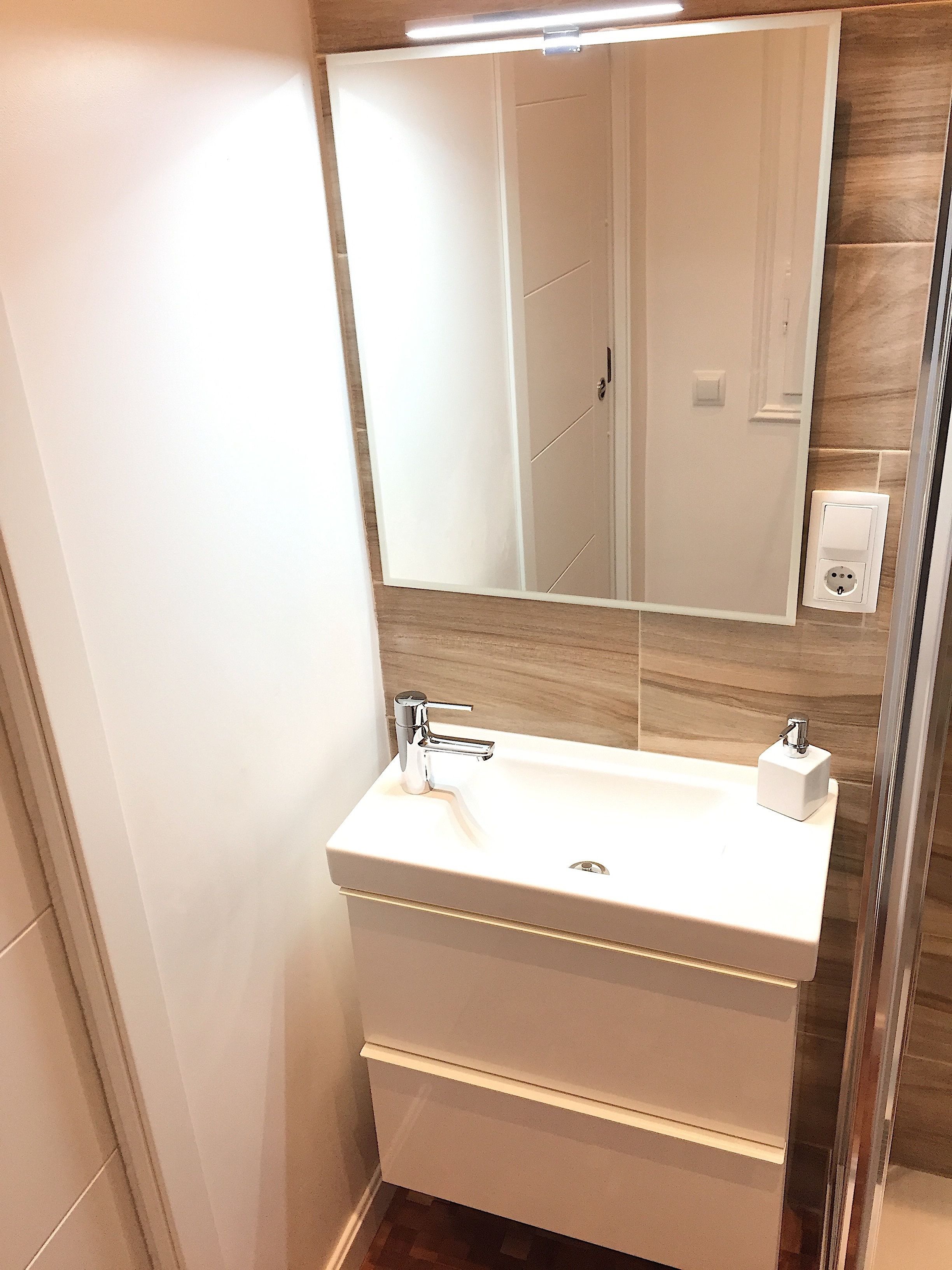 Un baño con tocador blanco, espejo y grifo moderno.