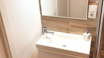 Un baño con tocador blanco, espejo y grifo moderno.