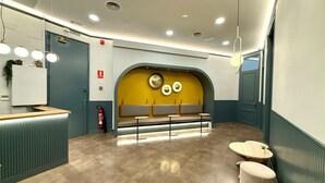 A modern reception area with a reception desk, seating area, and a clock on the wall. - Hip Karma Hostel (Barcelona)