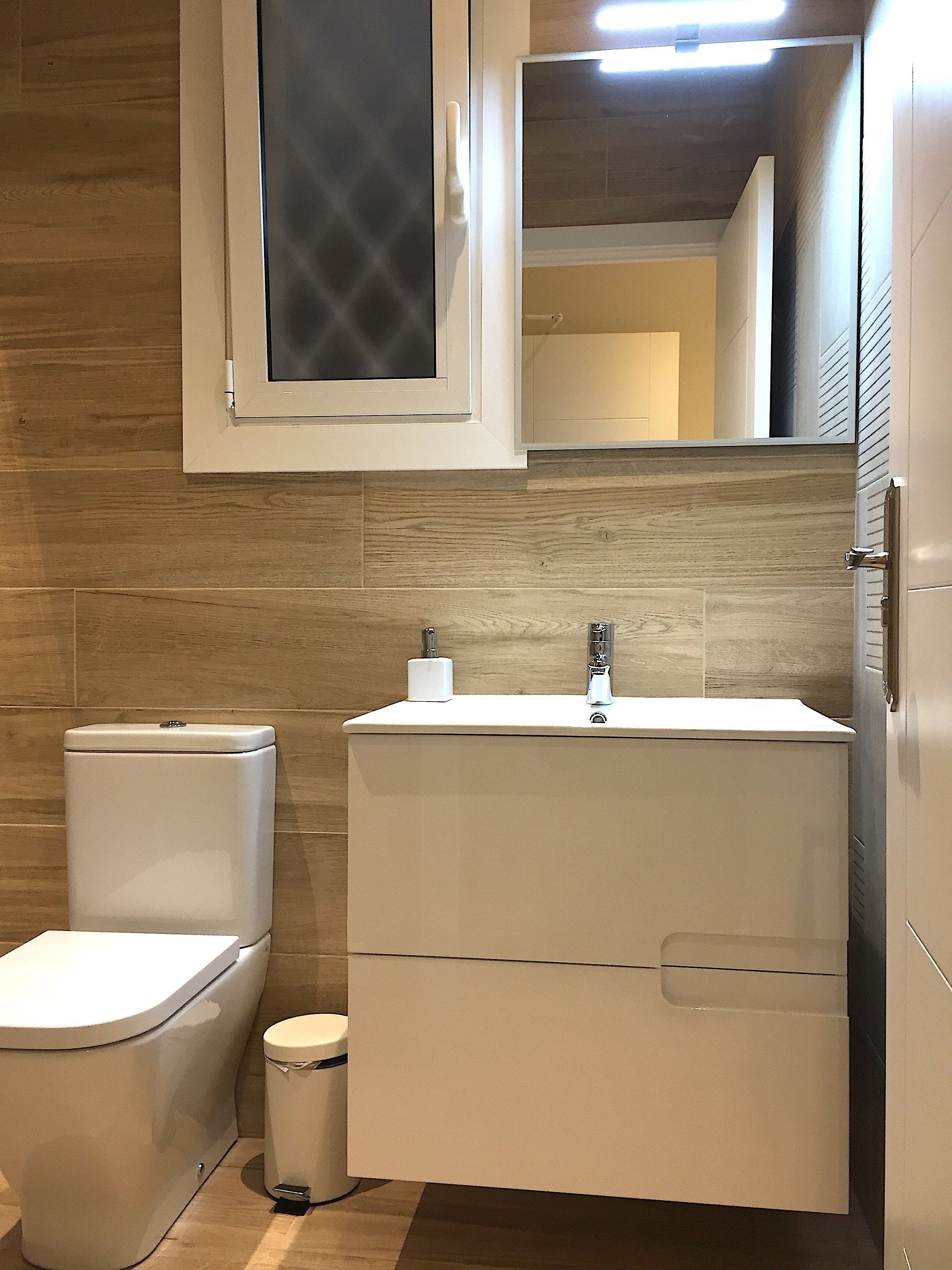 Un baño moderno con inodoro, lavamanos y espejo.
